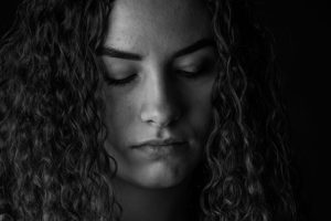 Woman with curly hair with eyes closed.