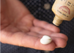 A hand squeezing a small amount of creme on an index finger.