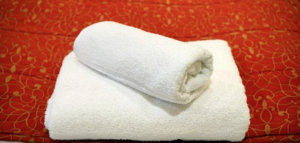 Two white towels folded on a red fabric.