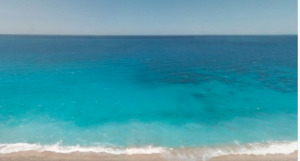 Blue-green ocean water lapping at golden sand on a sunny day.
