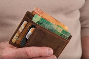 Male fingers holding a wallet with money and credit cards.