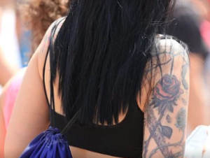 Woman with mid-back black hair and tattoo sleeve.