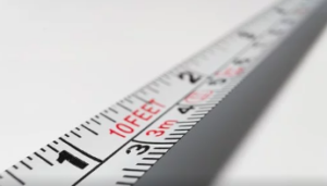 A white metal measuring tape with inches and centimetres.