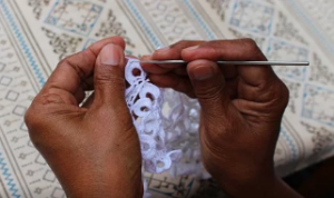 A pair of hands from someone of African descent crocheting a doily.