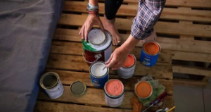Someone opening different cans of paint to do a wall.