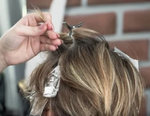 Hand applying light blonde highlights .
