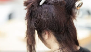 Person with dark-brown hair partially pinned up and waiting to be done.