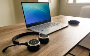 A computer with a headset and a mouse on a brown table.