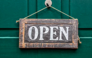 A wooden "Open" sigh on a hunter-green background