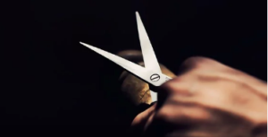 A hand holding open hair scissors.