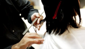 Hairstylist giving a haircut to client with black hair.