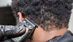 Person with super curly hair having the nape outlined with clipper.