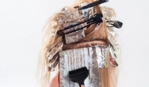 Person with dark blonde hair getting foil highlights.