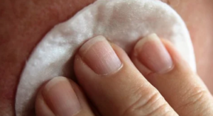Fingers on a cotton swab rubbing skin.