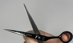 A hand holding a pair of scissors open.