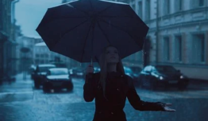 Silhouette of woman holding umbrella on the street in the rain.