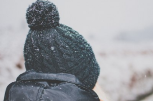 Back view of person wearing a blue-black tuque surrounded by snow.