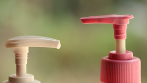 One beige and one pink shampoo bottle pump.