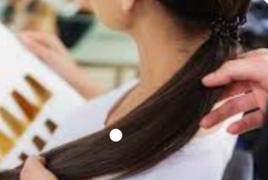 A client's medium brown hair being compared with a color chart.