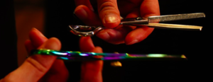 A pair of hands comparing two pairs of scissors.