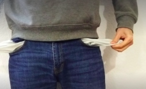 Lower body of male in a grey sweater and blue jeans with the pockets inside out.