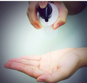 A hand squeezing shampoo from a white and black bottle into a palm.