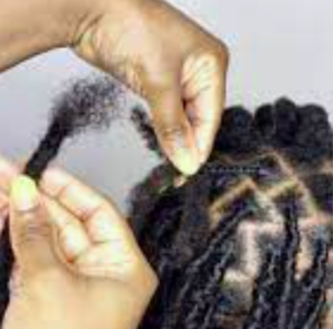 A pair of hands preparing to add black dreadlock extensions.