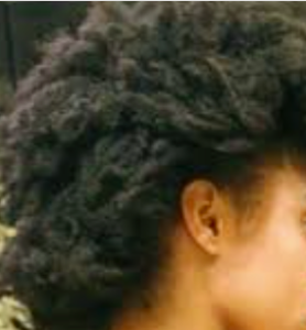 The side view of a person with black, super curly natural hair.
