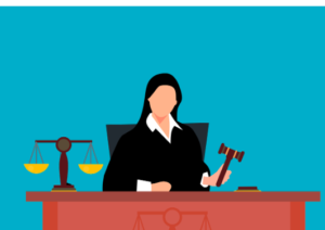 Silhouette of a female judge at a desk with a gavel and a balance.