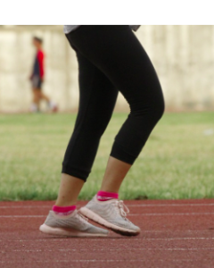 The legs of a person in black tights running on a track.