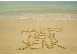 Happy New Year written in the sand at the water's edge