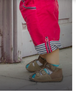 Toddlers legs in red pants with brown velcro sandals.