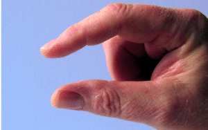 A hand held up with finger and thumb apart against a blue background