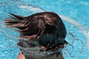 A kid with dark blond hair swirling in a pool.