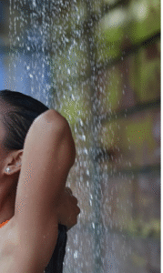 Water falling behind a female squeezing her hair in an outdoor shower.