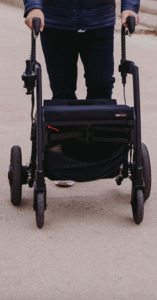 Person using a black 4-wheeled walker.