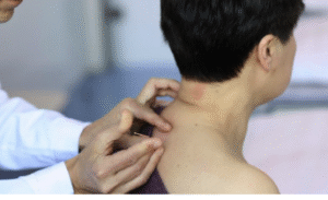 A doctor examining the back of a female's neck.