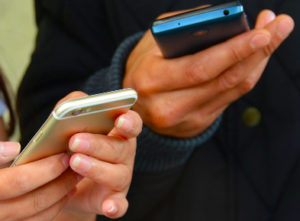 Hands of two people scrolling on cell phones.