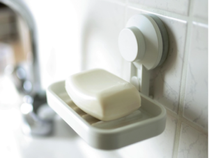 A white soap bar in a grey, hanging soap holder.