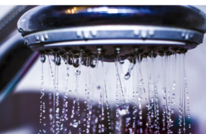 A silver round shower head raining water.
