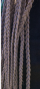 Long ash-grey braids hanging against a dark background
