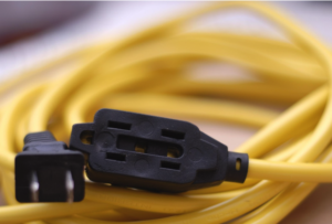 A coiled yellow extension cord with a three-outlet end