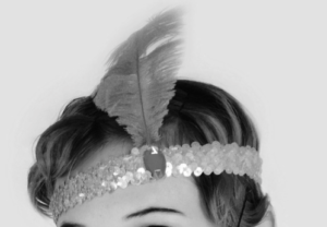 A female's hair held by a sequined band with a jewel on a feather.