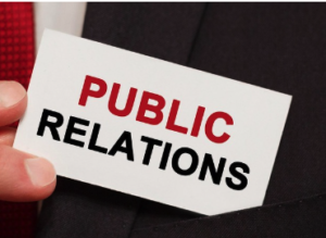 A hand holding a business card printed with the words Public Relations