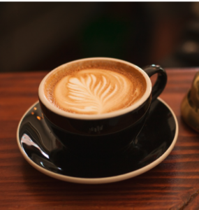 A cup of coffee with a milk leaf design.