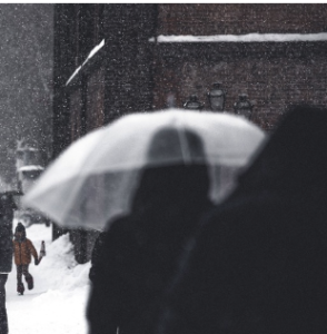 A blurred image of a person walking with a transparent umbrella.