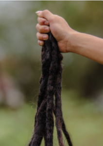 A hand holding a bunch of thick, dark-brown, long dread/locs.