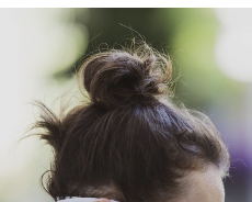 A small messy bun on dark blond hair.