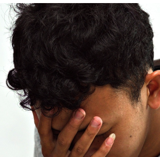 A person with black hair holding their head down in despair.